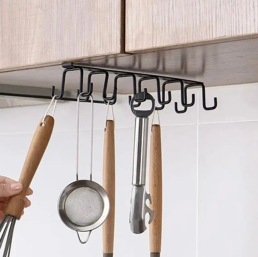Kitchen utensils hanging from a black over-the-cabinet hook organizer.