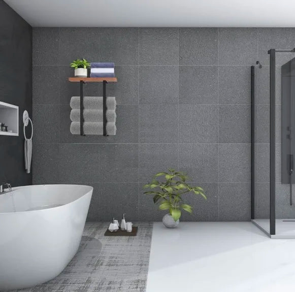 Modern bathroom with gray tiled walls, a white bathtub, and decorative elements.