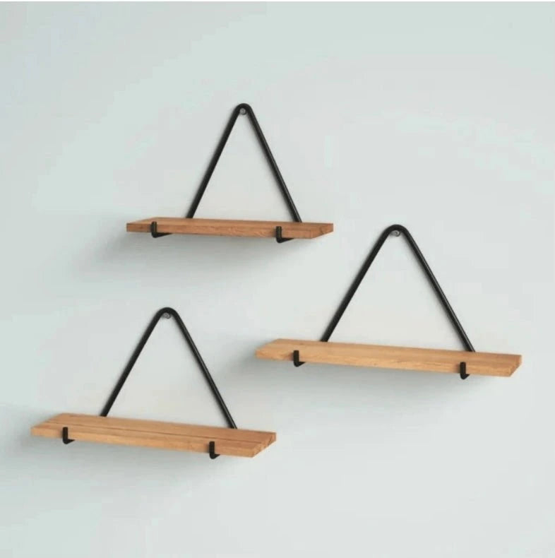 Set of three wooden shelves with black metal brackets on a light gray background