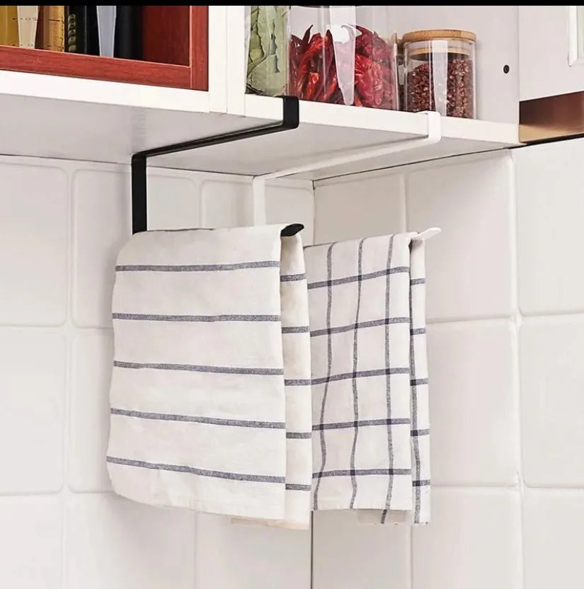 Towels hanging from a magnetic strip on a white tiled wall with shelves above.