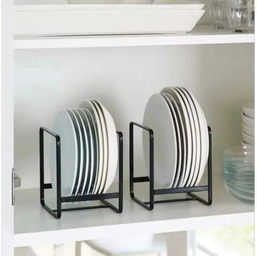 Two black plate racks holding stacked plates on a white shelf.