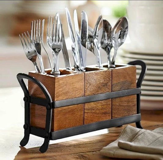 Wooden cutlery holder with silverware on a blurred kitchen background
